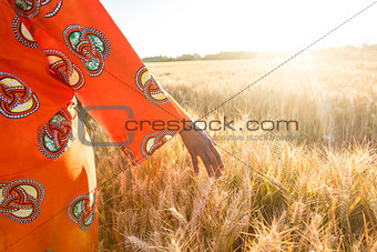 African woman in traditional clothes walking with her hand on a 