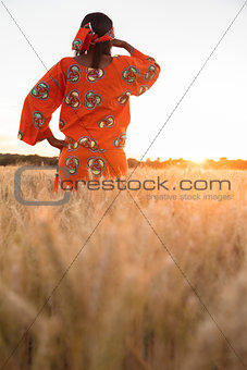 African woman in traditional clothes looking in a field of crops