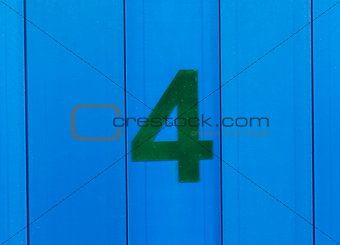 the number four, green, set against bright blue wood