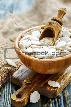 Unshelled pumpkin seeds in a wooden bowl.