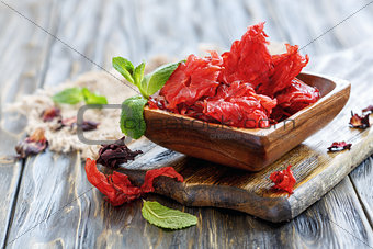 Dried hibiscus flowers in a wooden bowl.