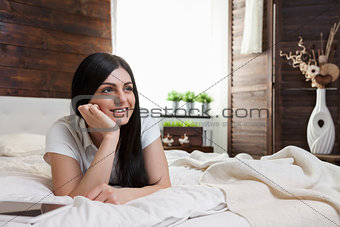 Beautiful woman relaxing on the bed and using her tablet