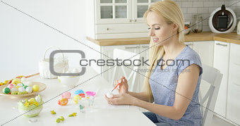Young girl painting eggs at kitchen
