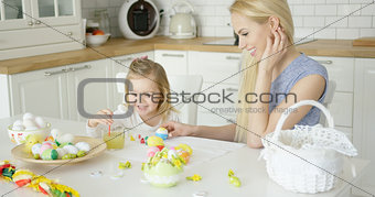 Laughing woman and little girl coloring eggs