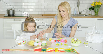 Charming mother and daughter coloring eggs