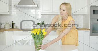 Woman arranging vase with flowers on table
