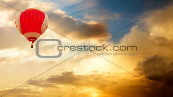 Hot Air Balloon Flying over Golden Sunset Sky