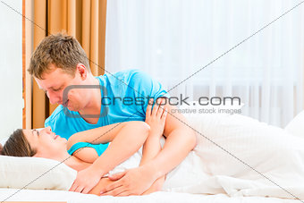 Happy couple flirting in bed before bedtime