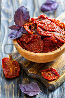Sun-dried tomatoes and red basil in a wooden bowl.
