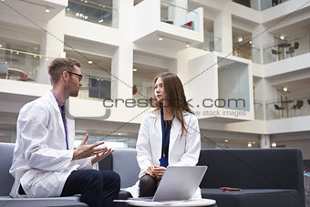 Two Doctors Having Meeting In Hospital Reception Area
