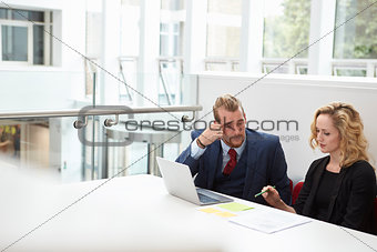 Two Businesspeople Using Laptop At Desk In Modern Office