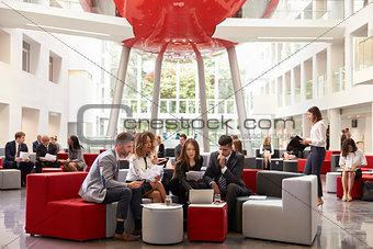 Businesspeople Meeting In Busy Lobby Of Modern Office