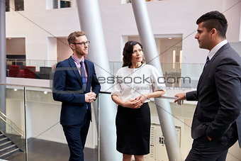 Businesspeople Meeting In Busy Lobby Of Modern Office