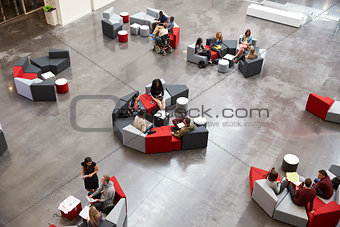 Students sit in groups in a modern university atrium
