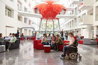 Student in wheelchair and colleagues in university lobby