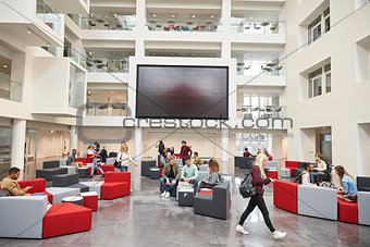 Students in front of screen in atrium of modern university