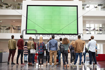Students looking up at a big screen in university building
