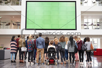 Students looking up at a big screen in university atrium