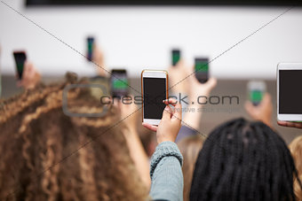 Young adults taking photos with phones, back view close up