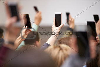 Hands in a crowd holding phones up to take pictures