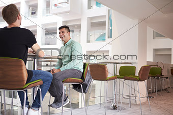 Adult male students talking at a university cafe, low angle