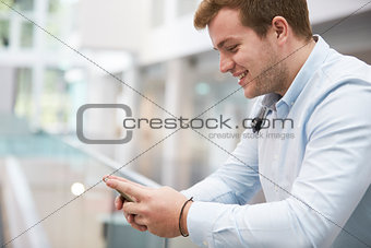 Adult male student using smartphone in university, close up