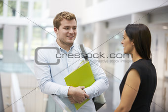 Adult student and teacher talking in university foyer