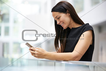 Young woman using smartphone in modern university interior