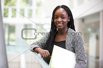Smiling young black female student in university foyer