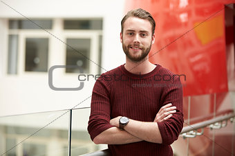 Smiling male adult student in modern university building