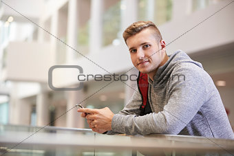 Young adult male student looks to camera in university lobby