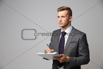 Studio Portrait Of Businessman Writing On Clipboard