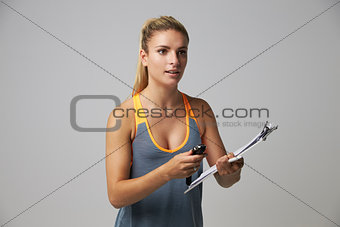 Studio Portrait Of Female Sports Coach With Clipboard