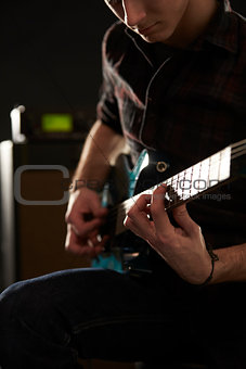 Close Up Of Man Playing Electric Guitar In Studio