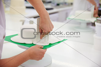 Close Up Of Woman In Bakery Decorating Cake With Royal Icing