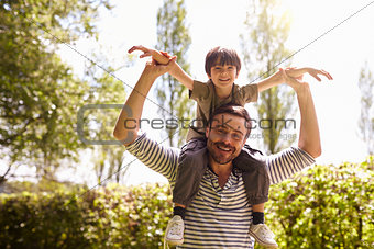 Father Giving Son Ride On Shoulders During Walk