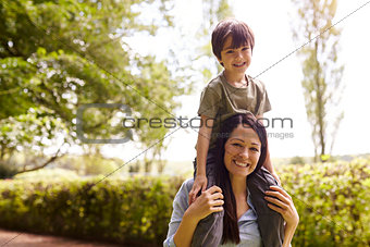 Mother Giving Son Ride On Shoulders During Walk