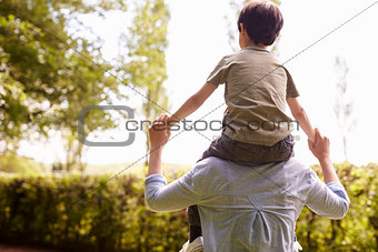 Rear View Of Mother Giving Son Ride On Shoulders During Walk