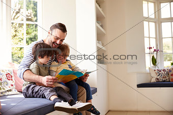 Father And Sons Reading Story At Home Together
