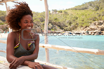 African American woman at a table by the sea, looking away