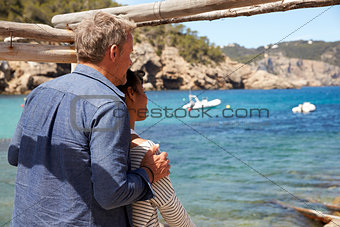 Mixed race couple looking out to sea from a jetty, back view