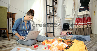 Woman with laptop in tailor's shop