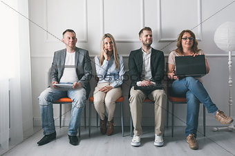 Group of creative people sitting on chairs in waiting room