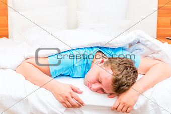 sleeping man on a white bed sheets