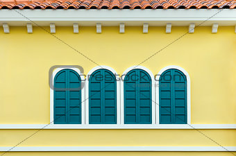 Four green arched windows on yellow wall
