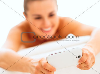 Closeup on young woman writing sms while laying on massage table