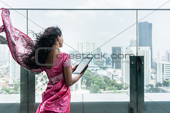 Young Indian woman using a tablet Pc on a terrace in a windy day