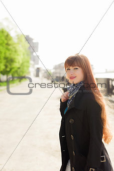 Beautiful red-haired young woman walking down the embankment on a sunny day, examining the neighborhood.