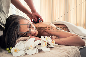 Young woman receiving hot stone massage at spa and wellness cent