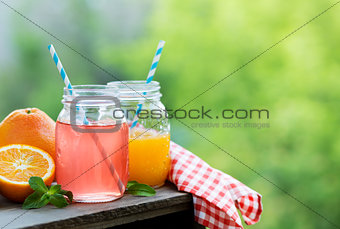 Grapefruit and orange juice in glass jars in the open air.